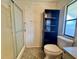 This bathroom features a walk-in shower with sliding glass door, toilet, storage cabinet, and window at 225 N Saint Thomas Cir, Apollo Beach, FL 33572