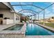 Enclosed pool featuring a waterfall hot tub, outdoor kitchen, and lush landscaping at 805 Islebay Dr, Apollo Beach, FL 33572