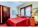 Bedroom with red bedding, wooden furniture, and hardwood floors at 115 Athens St, Tarpon Springs, FL 34689