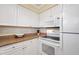 White kitchen with granite countertops and appliances at 19417 Gulf Blvd # C-211, Indian Shores, FL 33785