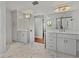 Dual-sink bathroom with white cabinets, herringbone tile floors, and a view of the glass shower at 307 Harbor View Ln, Largo, FL 33770