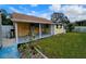 Yellow house with covered patio overlooks a well maintained backyard with a white fence under a sunny sky at 7211 Waycross Ave, Tampa, FL 33619