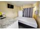Cozy bedroom features a kitchenette with granite countertop, refrigerator, air conditioner, and a mounted TV at 7211 Waycross Ave, Tampa, FL 33619