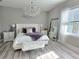 Luxurious bedroom with a white tufted headboard bed, chandelier, and wood-look floors at 122 W Sligh Ave, Tampa, FL 33604