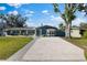 Blue house with a large driveway, green lawn, and mature trees at 1730 Audrey Dr, Clearwater, FL 33759