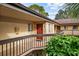 Exterior view of a condo with a red door on a balcony with brown railings and green foliage at 2679 Sabal Springs Cir # 203, Clearwater, FL 33761