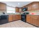 L-shaped kitchen with wood cabinets and black appliances at 8209 Rugby Ct, Hudson, FL 34667