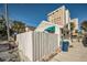 Side view of cottage with white fence and tall building at 822 Gulf Blvd # 4-6, Indian Rocks Beach, FL 33785