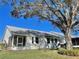 Home exterior showcasing a screened patio, lush lawn, and large oak tree at 9336 Villa Entrada, New Port Richey, FL 34655