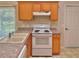 Kitchen with wood cabinets, white appliances, and granite countertops at 9336 Villa Entrada, New Port Richey, FL 34655