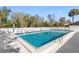 Large in-ground community pool with clear blue water, surrounded by a white fence, lounge chairs and palm trees at 3203 Audubon Ct, Tarpon Springs, FL 34688