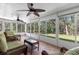 Enclosed sunroom with tile floor and walls of windows, furnished with wicker furniture, offering views of the surrounding greenery at 3203 Audubon Ct, Tarpon Springs, FL 34688