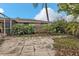 Backyard with a flagstone patio and overgrown shrubs at 512 Acacia Ln, Nokomis, FL 34275