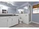 Bathroom with white cabinets, a large mirror, and shower at 512 Acacia Ln, Nokomis, FL 34275