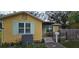 Charming yellow house with a covered porch, small deck, and a well-maintained lawn at 6404 Pershing Ne St, St Petersburg, FL 33702