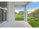 View from the covered patio into the fenced back yard with mature trees and green lawn at 4735 Rolling Green Dr, Wesley Chapel, FL 33543
