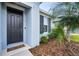 The home's entry has a black front door and is nicely landscaped with rocks and green plants at 4735 Rolling Green Dr, Wesley Chapel, FL 33543