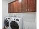 Laundry room featuring a white, front-load washer and dryer with dark brown cabinets above at 4735 Rolling Green Dr, Wesley Chapel, FL 33543