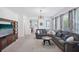 Bright living room featuring a large grey sectional sofa, carpeted floors, and ample natural light at 4735 Rolling Green Dr, Wesley Chapel, FL 33543