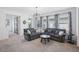 Bright living room featuring a large grey sectional sofa, carpeted floors, and ample natural light at 4735 Rolling Green Dr, Wesley Chapel, FL 33543