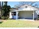 Home features a covered patio, lush lawn, and mature trees at 8040 Pasadena Dr, Port Richey, FL 34668