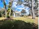 Large backyard with mature trees and a partially covered patio at 8040 Pasadena Dr, Port Richey, FL 34668