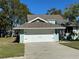 Well-maintained light green house with a white garage door and neatly trimmed lawn at 1005 Lake Avoca Pl, Tarpon Springs, FL 34689