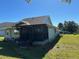 Back exterior showcasing a screened porch, lawn, and mature trees at 1005 Lake Avoca Pl, Tarpon Springs, FL 34689