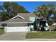 Cute light green house with a white garage door and well-maintained lawn at 1005 Lake Avoca Pl, Tarpon Springs, FL 34689