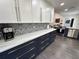 Modern kitchen boasts white and dark blue cabinetry, quartz countertops and patterned backsplash at 1005 Lake Avoca Pl, Tarpon Springs, FL 34689