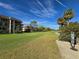 Scenic golf course view with lush green grass, palm trees, and blue skies adjacent to multi-story condominium buildings at 3031 Countryside Blvd # 35C, Clearwater, FL 33761