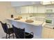 Bright kitchen with white cabinetry, tile backsplash, breakfast bar with seating, and modern appliances at 3031 Countryside Blvd # 35C, Clearwater, FL 33761
