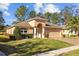 Inviting single-Gathering home features a well-kept lawn, arched entryway with stately columns, a paver driveway, and a two-car garage at 4275 Caskie Pl, Brooksville, FL 34604