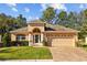 Welcoming single-Gathering home features a manicured lawn, arched entry, two-car garage, and a paver driveway, exuding curb appeal at 4275 Caskie Pl, Brooksville, FL 34604