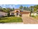 Inviting home featuring a manicured lawn, arched entry, and paver driveway, complemented by lush landscaping and a two-car garage at 4275 Caskie Pl, Brooksville, FL 34604