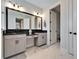 Bright bathroom featuring tile flooring, a dual sink vanity with black countertop, large mirror, and access to the toilet room at 9152 Warm Springs Cir, Parrish, FL 34219