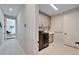 Hallway leading to laundry room with modern washer and dryer, as well as a bedroom with a ceiling fan at 9152 Warm Springs Cir, Parrish, FL 34219