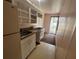 Galley kitchen with white appliances, laminate countertops and open shelving near an exterior door at 1319 Vance Rd, Plant City, FL 33566