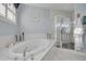 Elegant bathroom featuring a soaking tub, tiled floors, and a glass block shower with a palm tree at 238 71St Ave, St Pete Beach, FL 33706