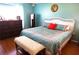 Comfortable main bedroom featuring a white wicker headboard, wood floors, and a cozy bench at 11021 Edge Park Dr, Hudson, FL 34667