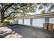 Attached garages feature white doors and a paved driveway, with a mature tree providing ample shade at 11805 Northtrail Ave, Temple Terrace, FL 33617