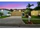 Charming two-story home with a well-manicured lawn, palm trees, and a three-car garage at 15815 Muirfield Dr, Odessa, FL 33556