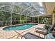 Refreshing pool surrounded by a screened enclosure, lounge chairs, and lush landscaping at 15815 Muirfield Dr, Odessa, FL 33556