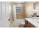 Well-lit bathroom featuring a tub shower with tile surround, cherry vanity, and toilet at 20314 Chestnut Grove Dr, Tampa, FL 33647