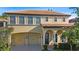 Elegant two-story home featuring a clay tile roof, arched entryway, attached two-car garage, and manicured landscaping at 20314 Chestnut Grove Dr, Tampa, FL 33647