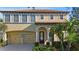 Two-story home showcasing a tile roof, tan stucco, arched entry, manicured landscaping, and a two-car garage at 20314 Chestnut Grove Dr, Tampa, FL 33647