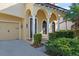 A charming front porch featuring a dark wooden door, decorative columns, and manicured shrubbery alongside the driveway at 20314 Chestnut Grove Dr, Tampa, FL 33647