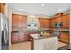 Open kitchen with wood cabinets, tile backsplash, granite countertops, stainless steel appliances, and tile floors at 20314 Chestnut Grove Dr, Tampa, FL 33647
