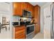 Close up of modern stainless steel oven and cooktop with wooden cabinetry and tile backsplash at 7233 15Th Ne Ct, St Petersburg, FL 33702