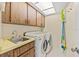 Well-equipped laundry room with washer, dryer, sink, storage cabinets, and practical cleaning supplies at 7233 15Th Ne Ct, St Petersburg, FL 33702